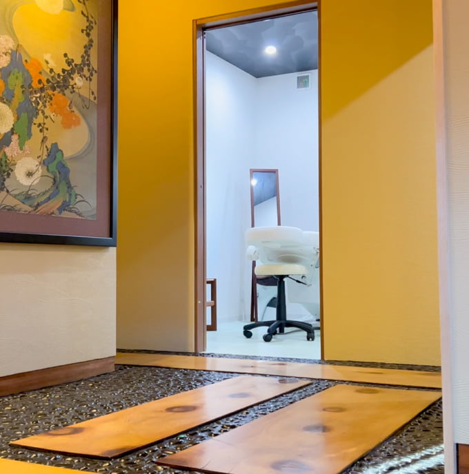 伊藤若冲の絵が飾られた廊下から見える施術室の入口