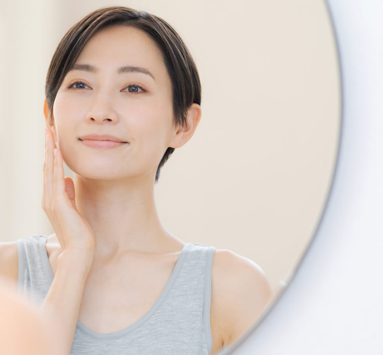 シワが気になり鏡をみている女性